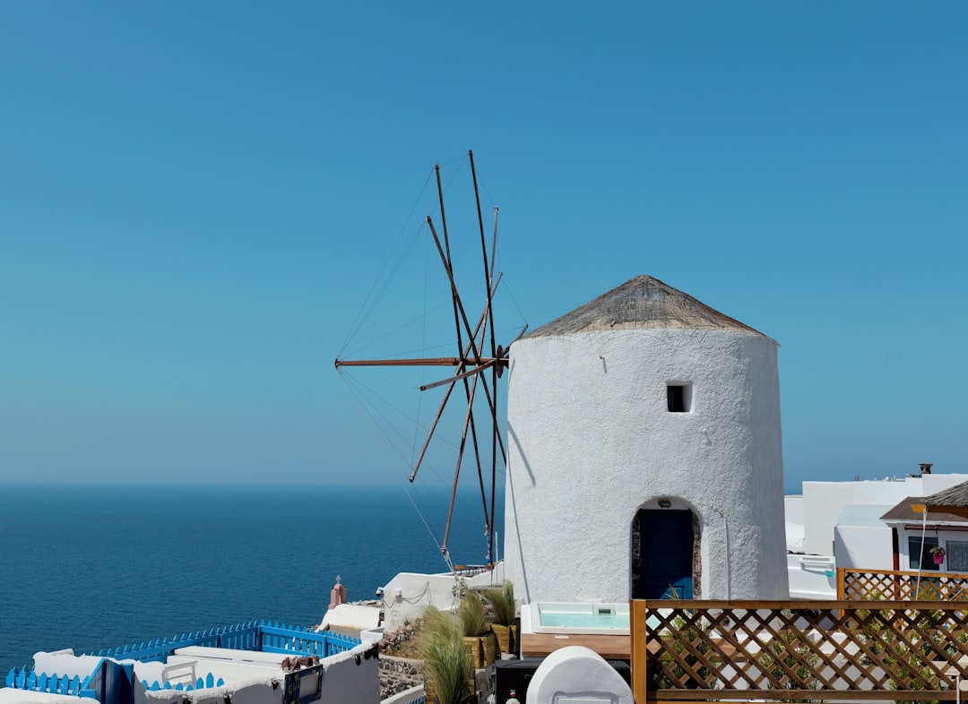 White windmill overlooking the blue ocean under clear sky