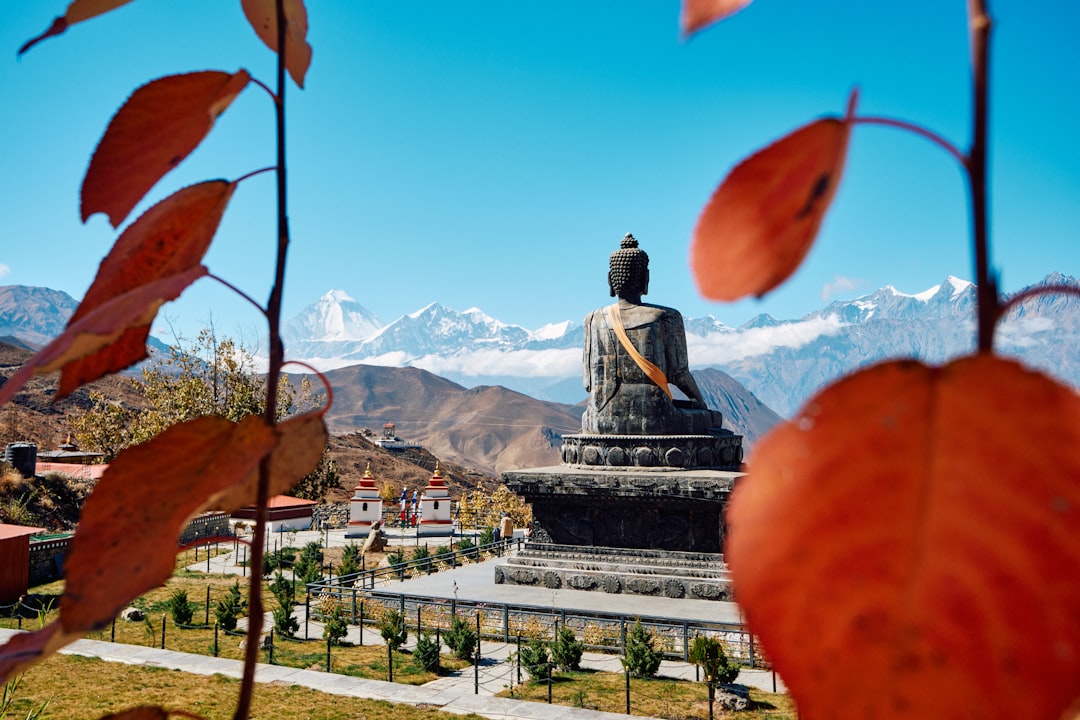 Giant buddha statue with snow-capped mountains behind.