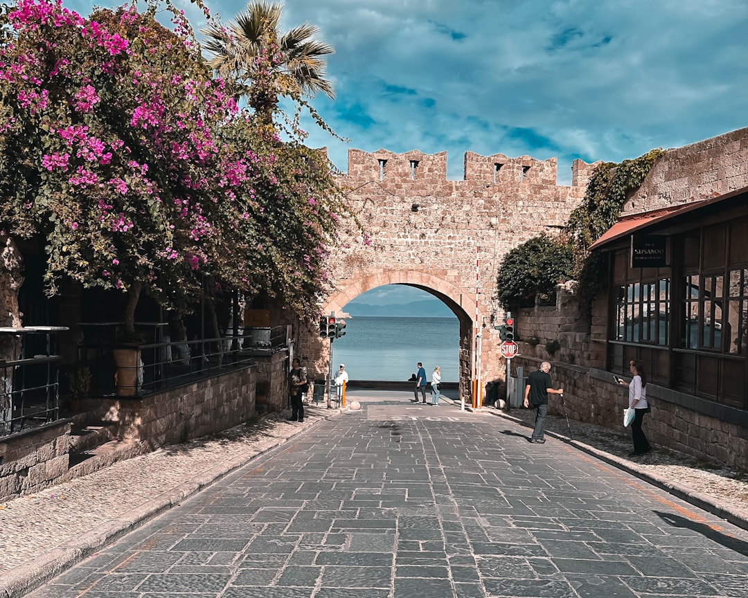 a cobblestone street with a stone arch leading to the ocean