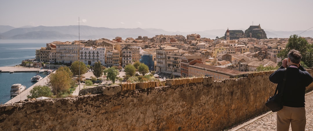 a person standing on a stone wall overlooking a city and water