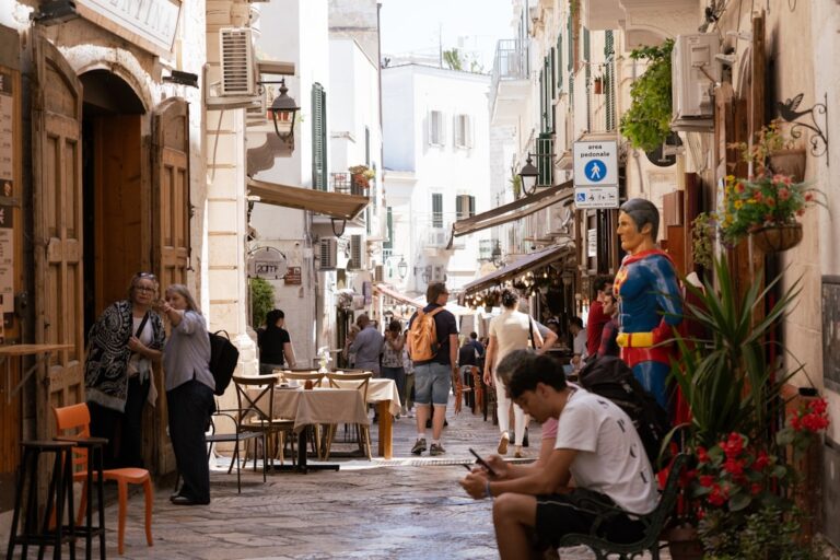 People walking down a narrow european street with shops.