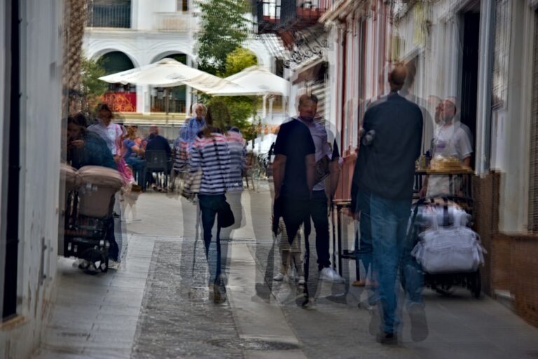 People walking down a narrow street with shops.