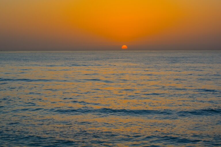 the sun is setting over the ocean